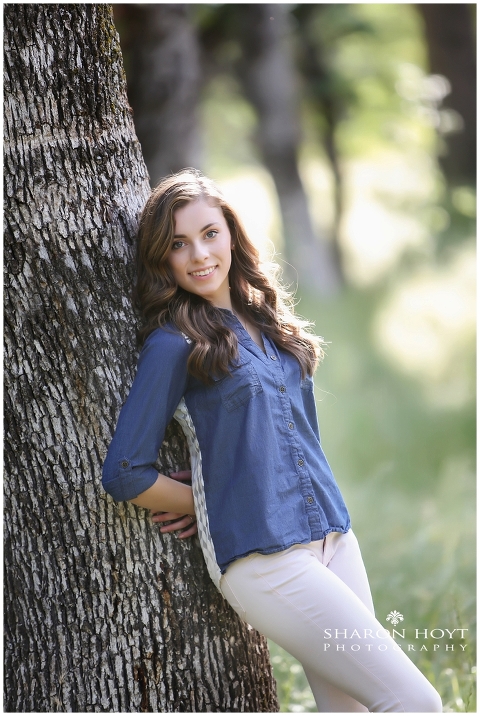 high school senior girl standing next to a tree